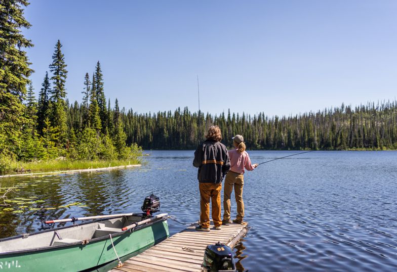 People fishing from the wharf next to a boat on a peaceful lake at Caverhill Lodge